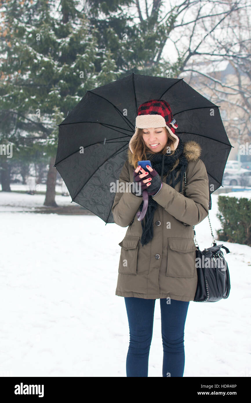 Frau schreiben SMS im tief verschneiten park Stockfoto