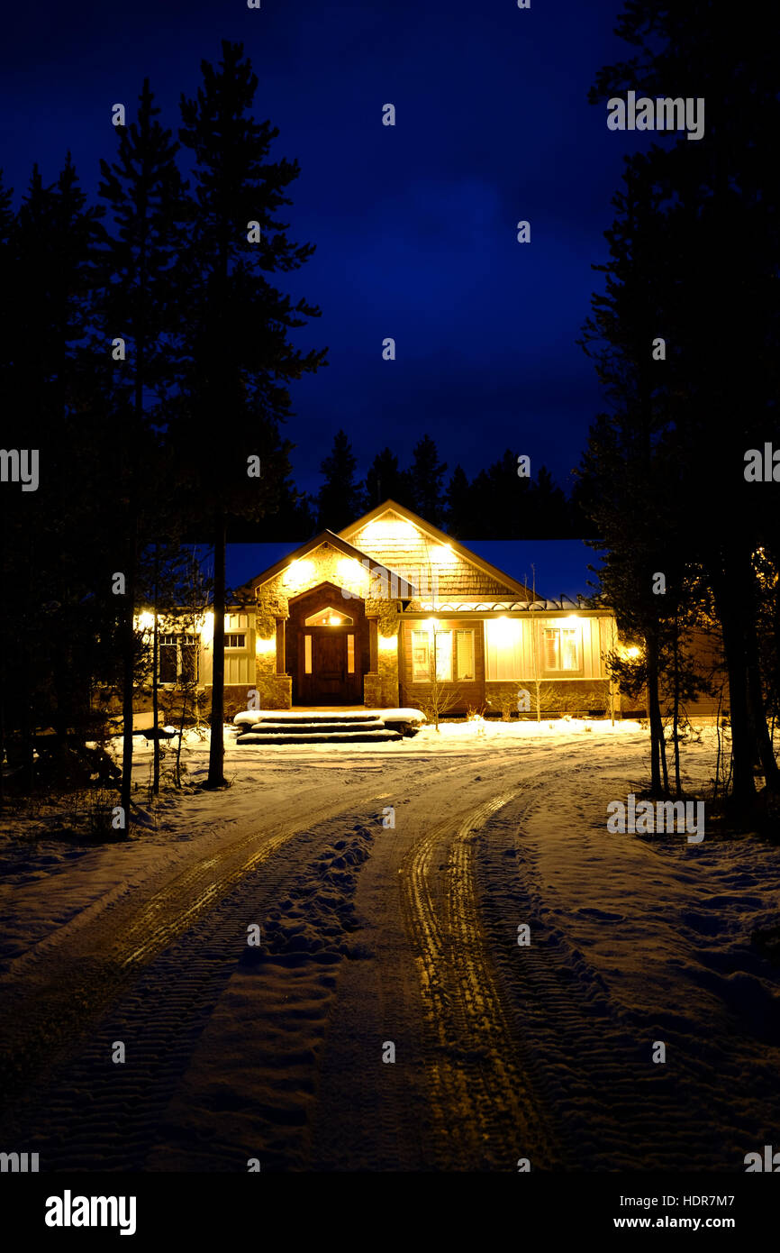 Kabine in Stand von Kiefern mit Schnee im Winter am Abend mit blauem Himmel bedeckt Stockfoto