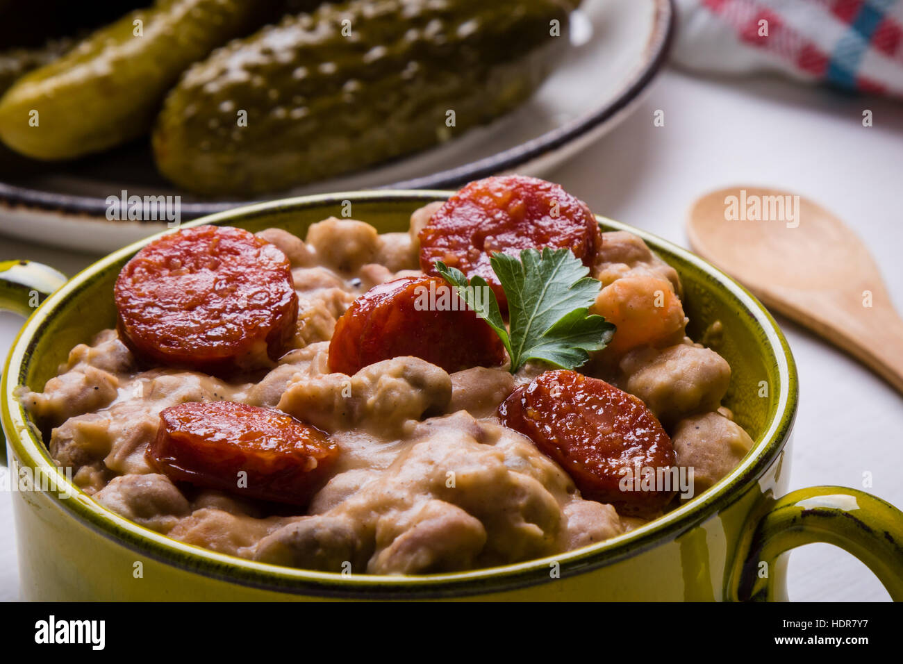 Bohnen-Eintopf mit Würstchen in grüner Schale Stockfoto