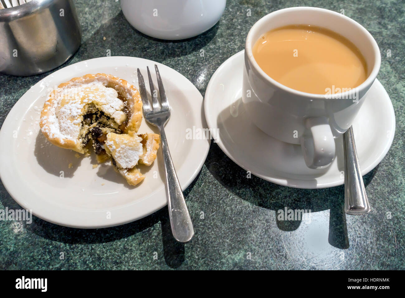 Winter-Snack in einer Yorkshire Café Tasse Tee und einem frisch gebackenen Mince Pie mit Zucker bestreut und aufgeschnitten Stockfoto