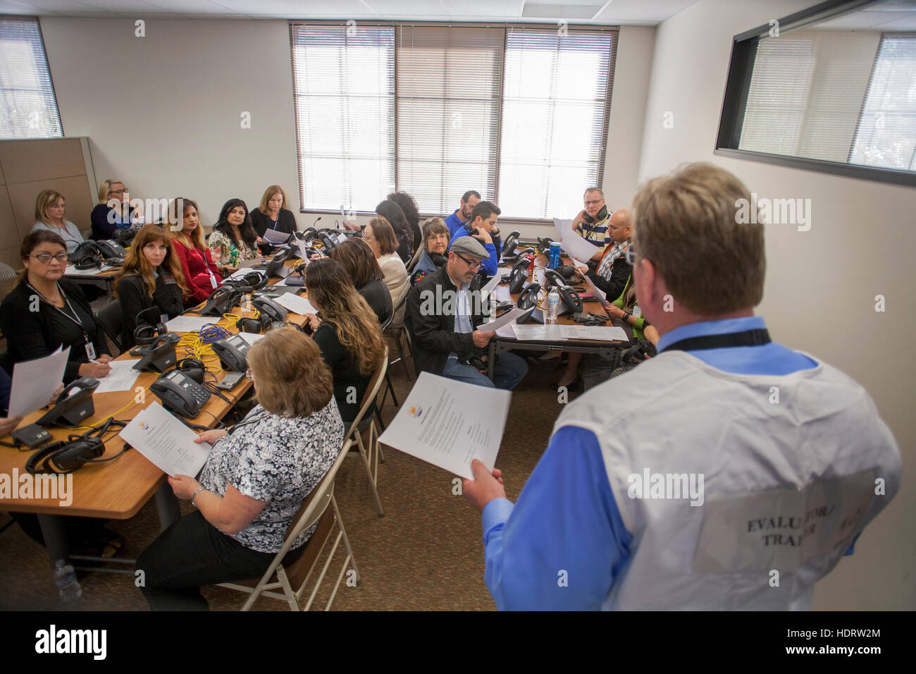 Multirassische Freiwillige Lehrer nehmen an einer Emergency Operations Center Praxis Alarm Telefon Bank in San Juan Capistrano, Kalifornien, mit potenziellen terroristischen Bedrohungen umzugehen. Hinweis-Administrator im Vordergrund. Stockfoto