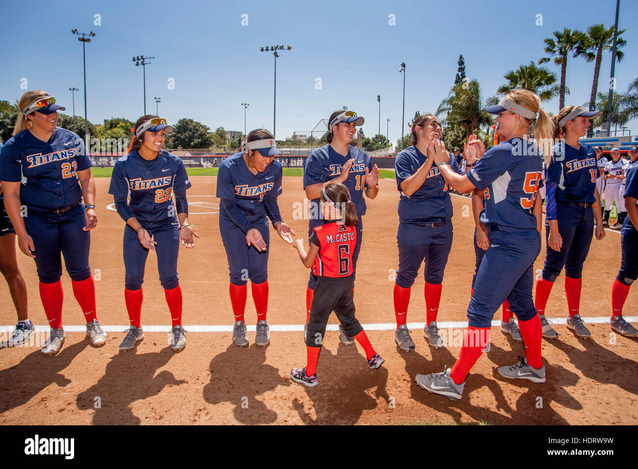 Gemischtrassig Studentinnen Softball Spieler Händedruck mit einem jungen Mädchen Verehrer Vorbereitung auf ein Spiel auf dem Feld in Fullerton, Kalifornien. Stockfoto