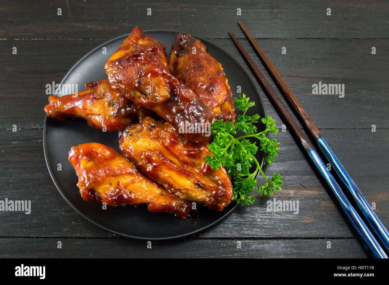 BBQ Chicken Wings und Stäbchen auf einem schwarzen Holztisch Stockfoto