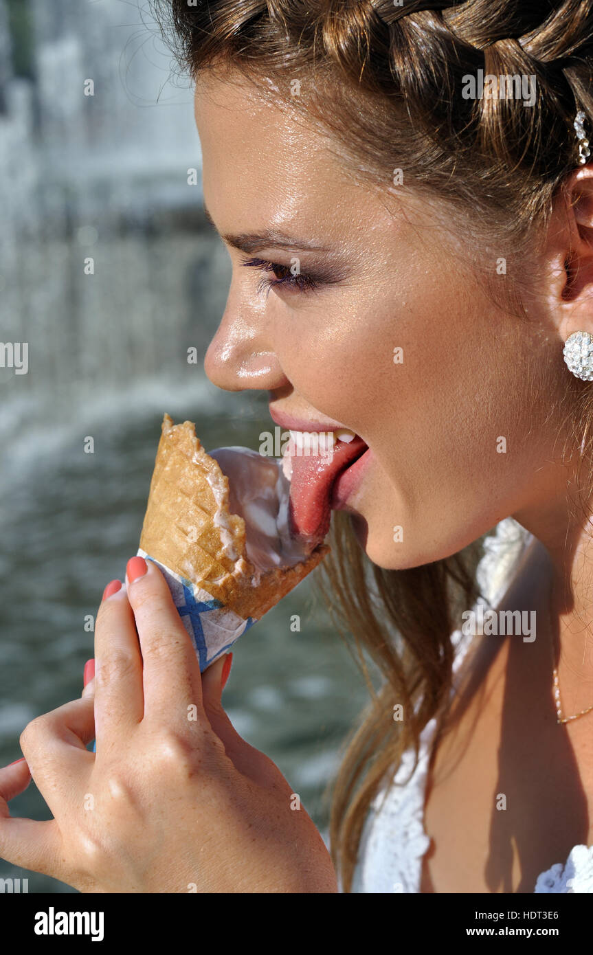 junge hübsche Frau, Eis essen, in der Nähe des Brunnens Stockfoto