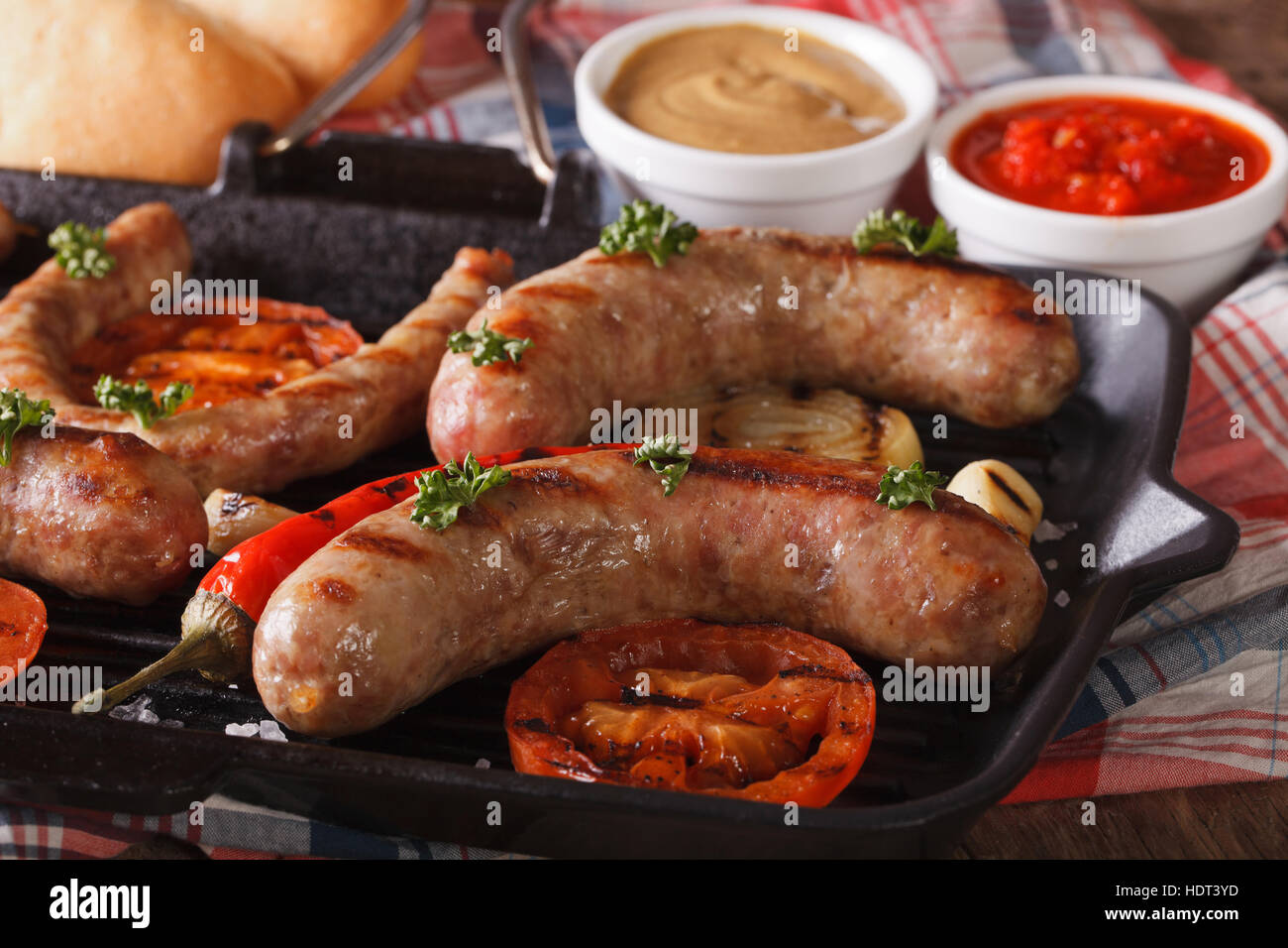 Hot Dog kochen: Gegrillte Würstchen, Gemüse in einer Pfanne grill, Brötchen  mit Soße auf den Tisch-Nahaufnahme. horizontale Stockfotografie - Alamy