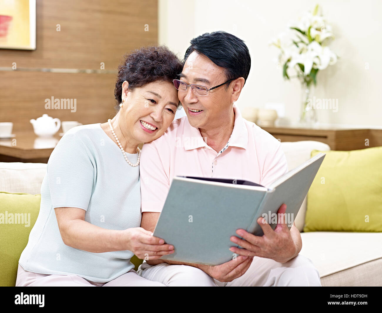 Senior asiatischen paar sitzt auf einem Buch zusammen, glücklich und lächelnd couch Stockfoto