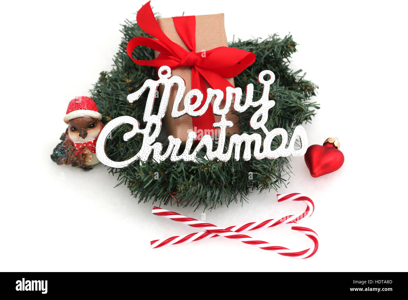 Ein Weihnachtsgeschenk im Kranz mit Weihnachtsschmuck und das Wort Frohe Weihnachten Stockfoto