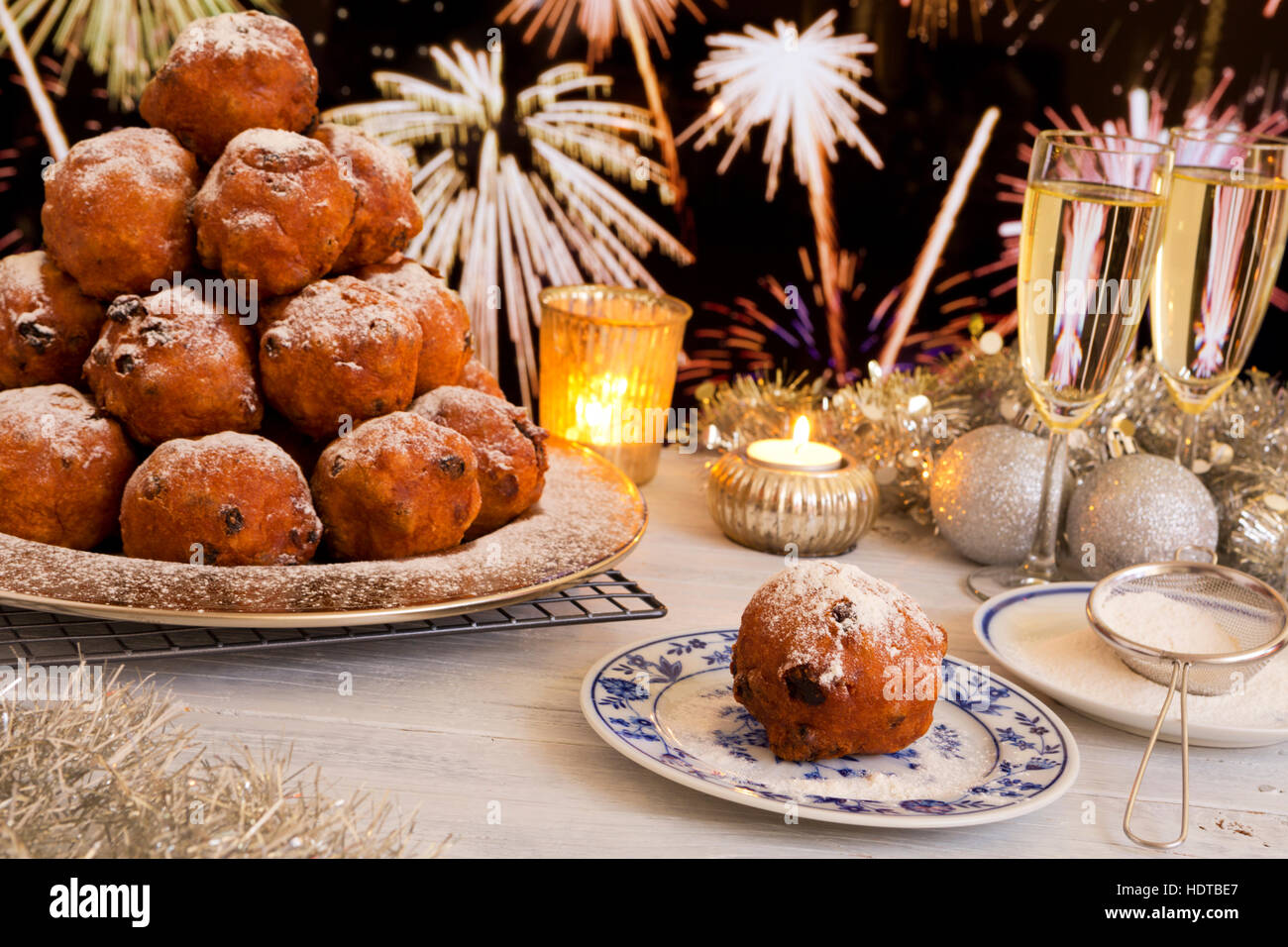 "Oliebollen", traditionelle holländische Blätterteig für Silvester. Mit Champagner und Feuerwerk im Hintergrund. Stockfoto