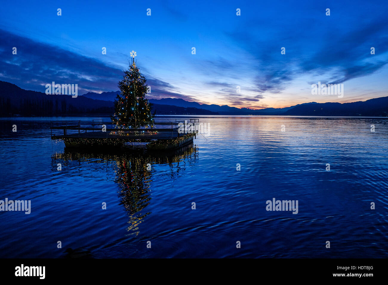 Weihnachtsbaum auf einem Ponton schwimmend am Wörthersee in Österreich. Frieren Sie ein-Aktion - Wellen sichtbar auf See. Stockfoto