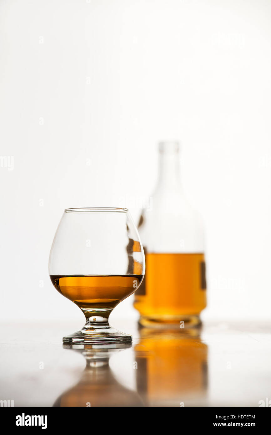 Cognac im Glas mit Flasche auf weißem Hintergrund Stockfoto