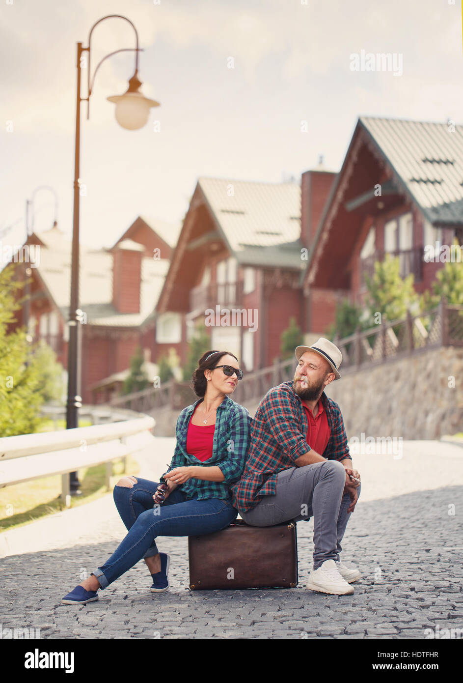 paar in Liebe sitzen auf der Straße mit Koffer Stockfoto