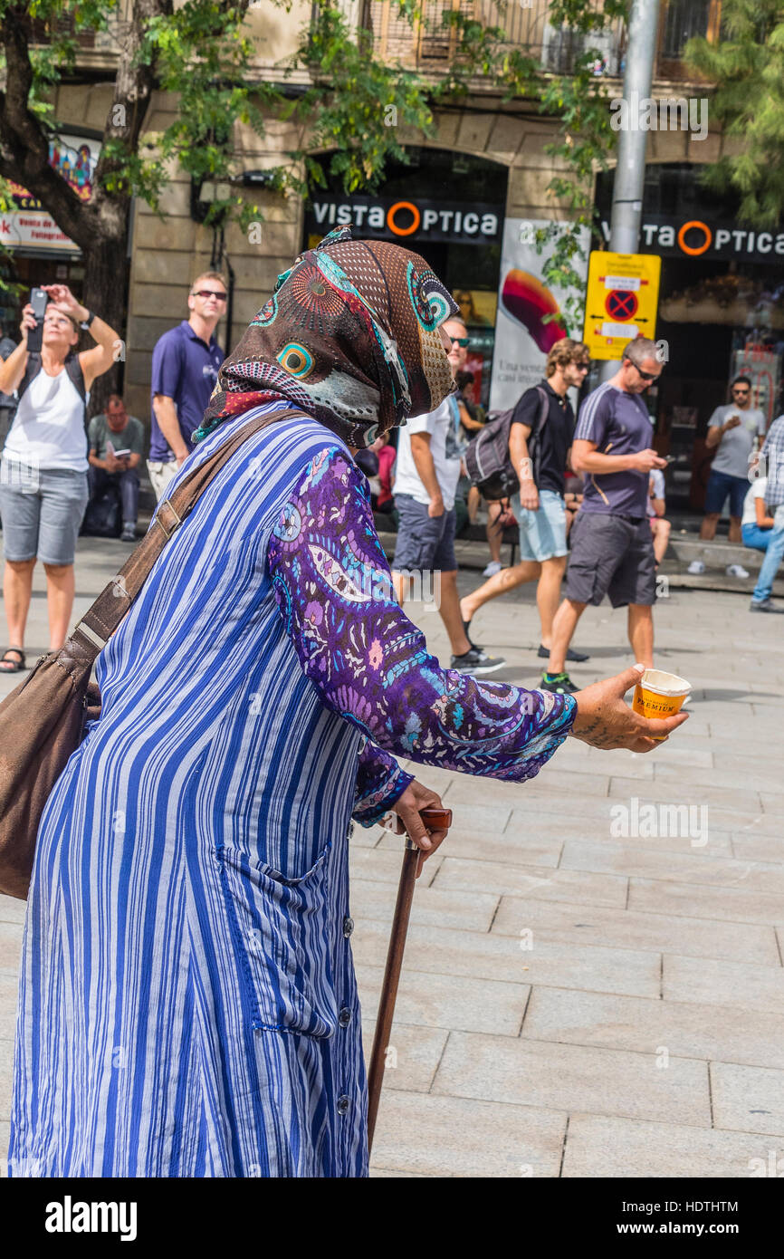 Muslimische ältere Frau Bettler gekleidet in eine Burka Betteln auf einem Platz in Barcelona, Spanien Stockfoto