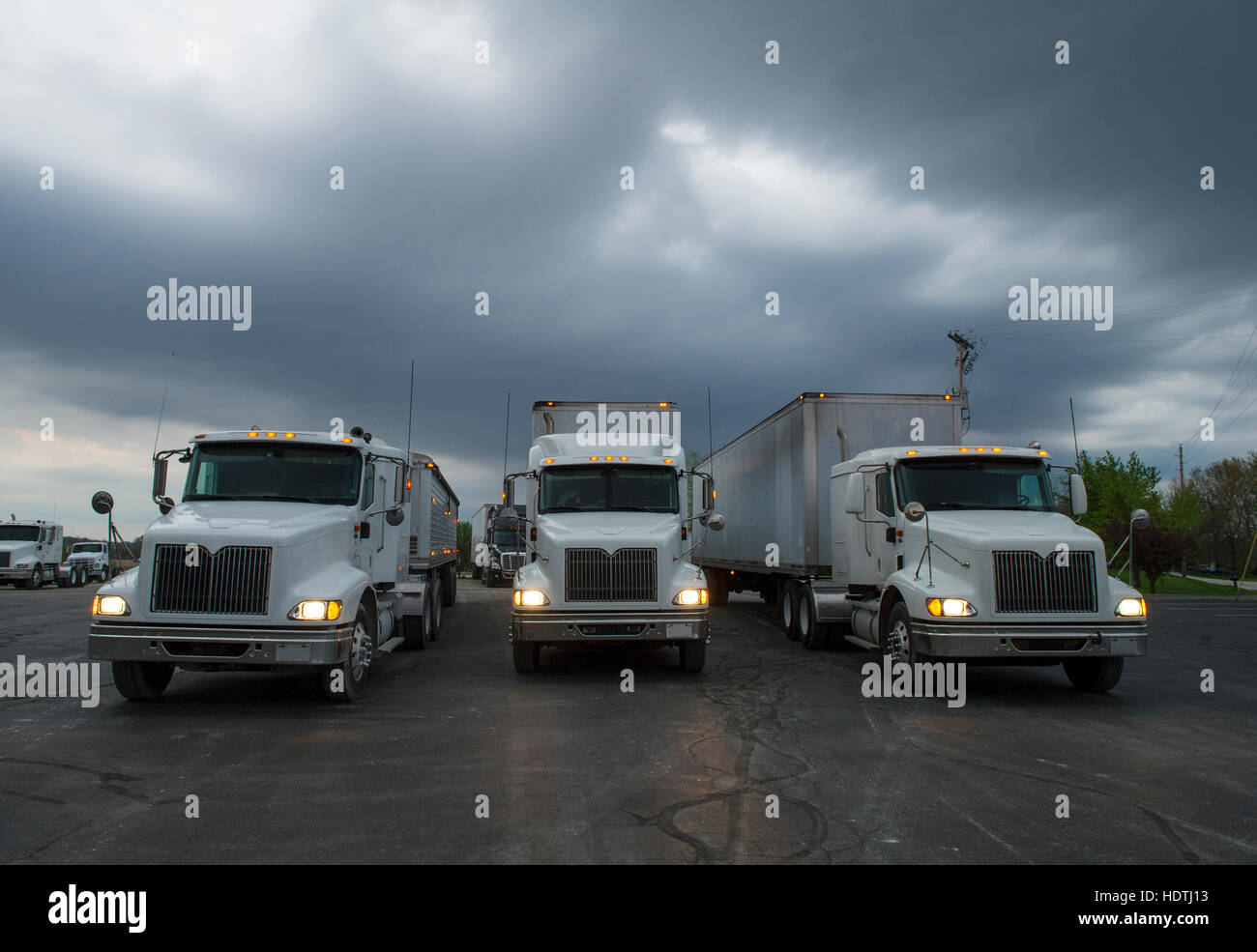 Drei halb Sattelzug LKW im Leerlauf auf einem Parkplatz auf einem Sturm droht am Abend. Stockfoto