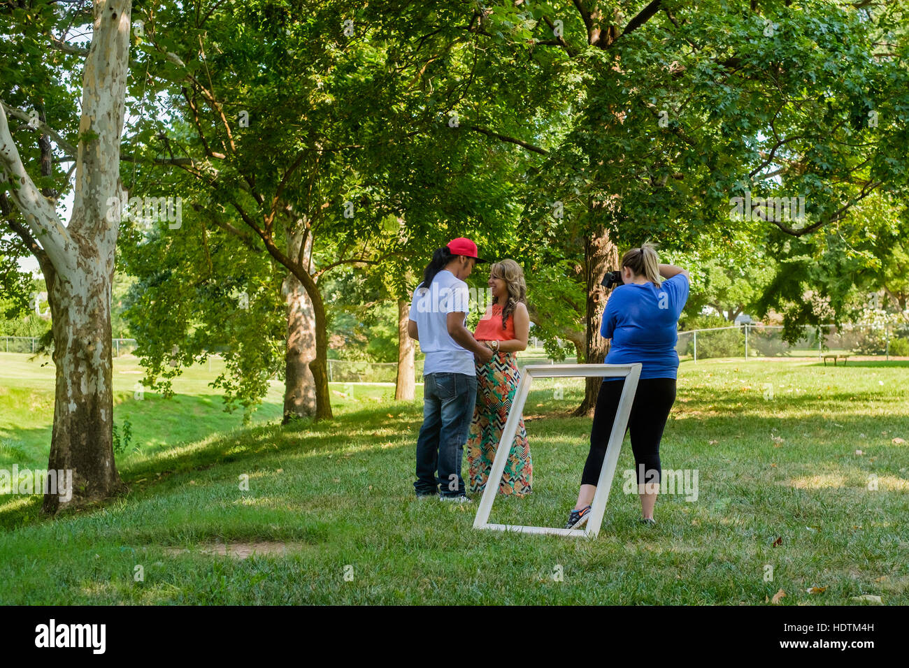 Eine ethnische paar darstellen, während eine Fotografin nimmt ihr Bild im Freien in einem Park. Oklahoma City, Oklahoma, USA. Stockfoto