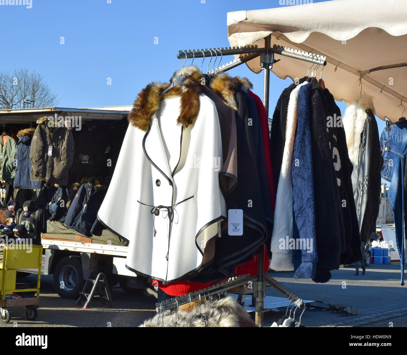 Capes und Mäntel hängen auf einem Gestell in einem Kleidung stand auf einem Wochenmarkt im ländlichen Frankreich. Stockfoto