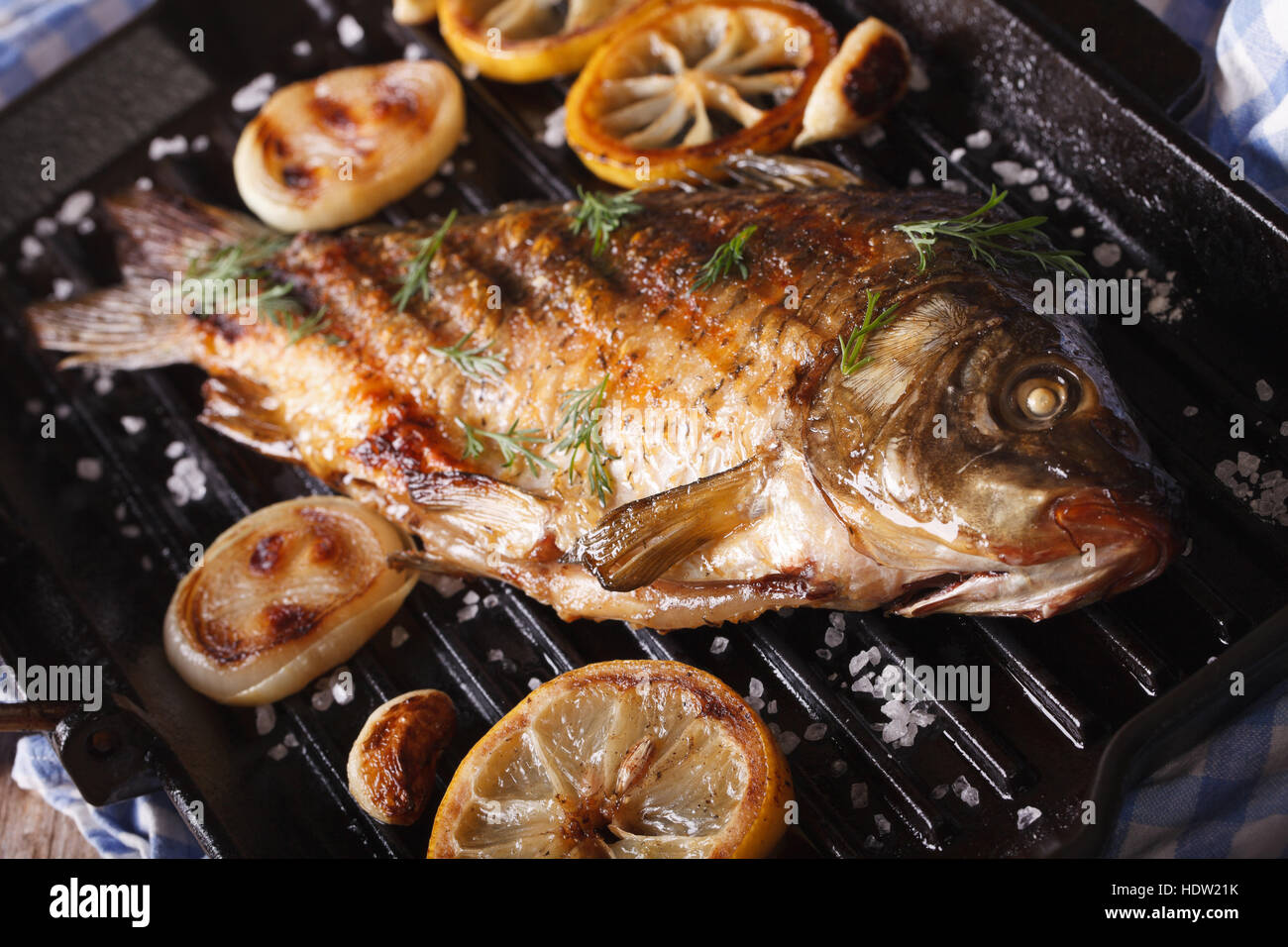 gebratenen Fisch Karpfen mit Zitrone und Zwiebel auf Grillpfanne, horizontale Nahaufnahme, rustikalen Stil Stockfoto