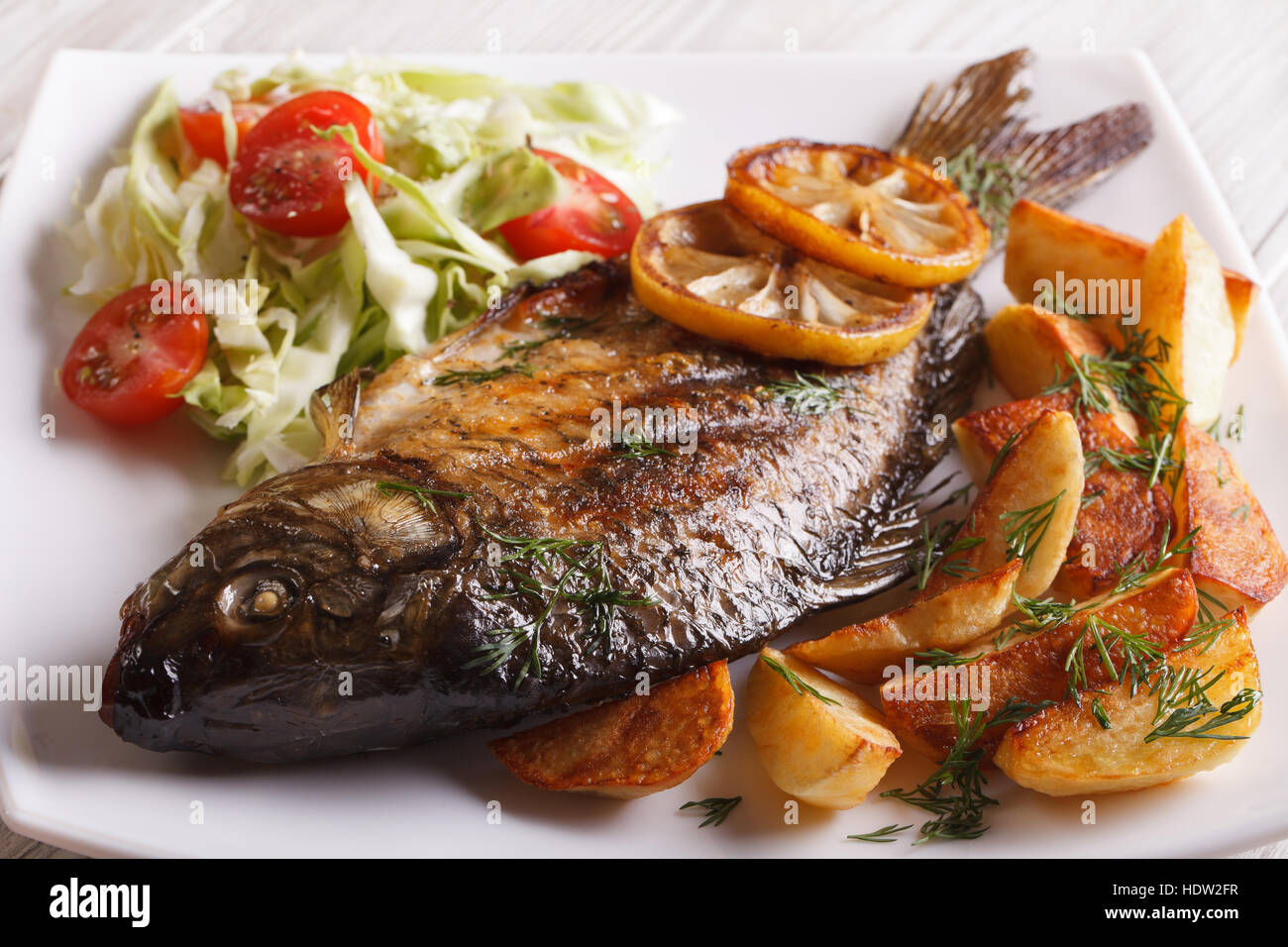 gebratenen Fisch Karpfen mit Kartoffeln und Salat auf eine Platte Nahaufnahme. horizontale Stockfoto