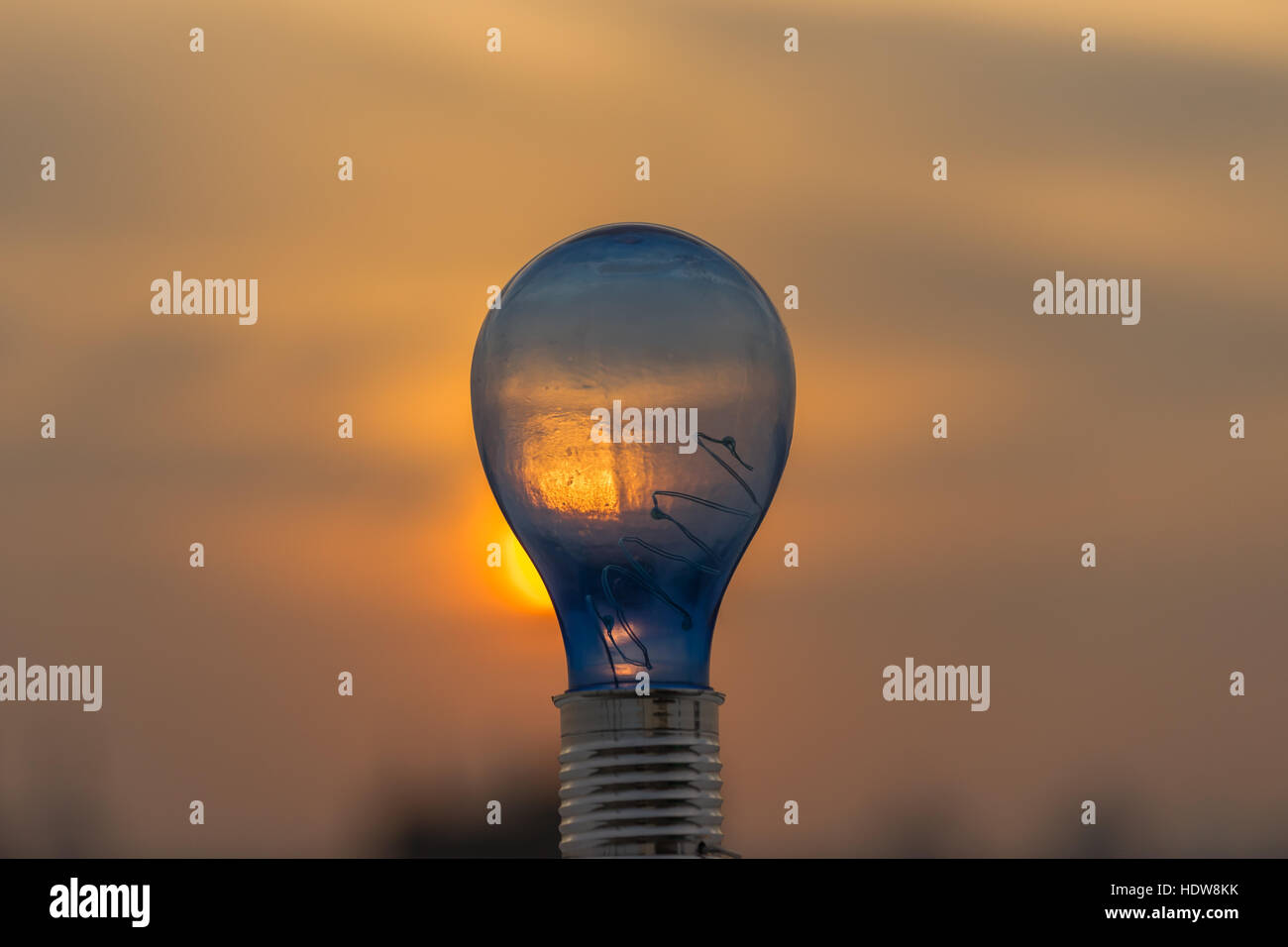 Geniale Idee, Glühbirne und Sonnenuntergang Hintergrund. Stockfoto