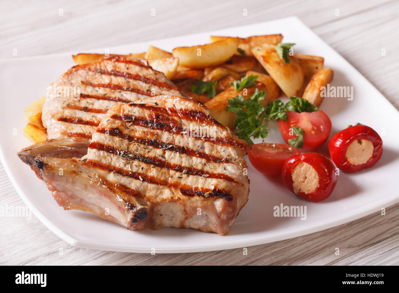 Gegrilltes Schweinesteak mit Kartoffeln und Gemüse auf einer Platte Nahaufnahme. horizontale Stockfoto