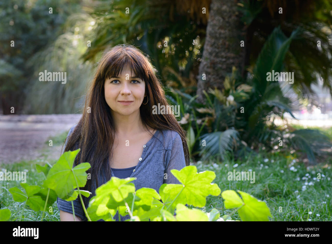 Ein nettes Mädchen posiert in einem Garten mit Grünpflanzen Stockfoto