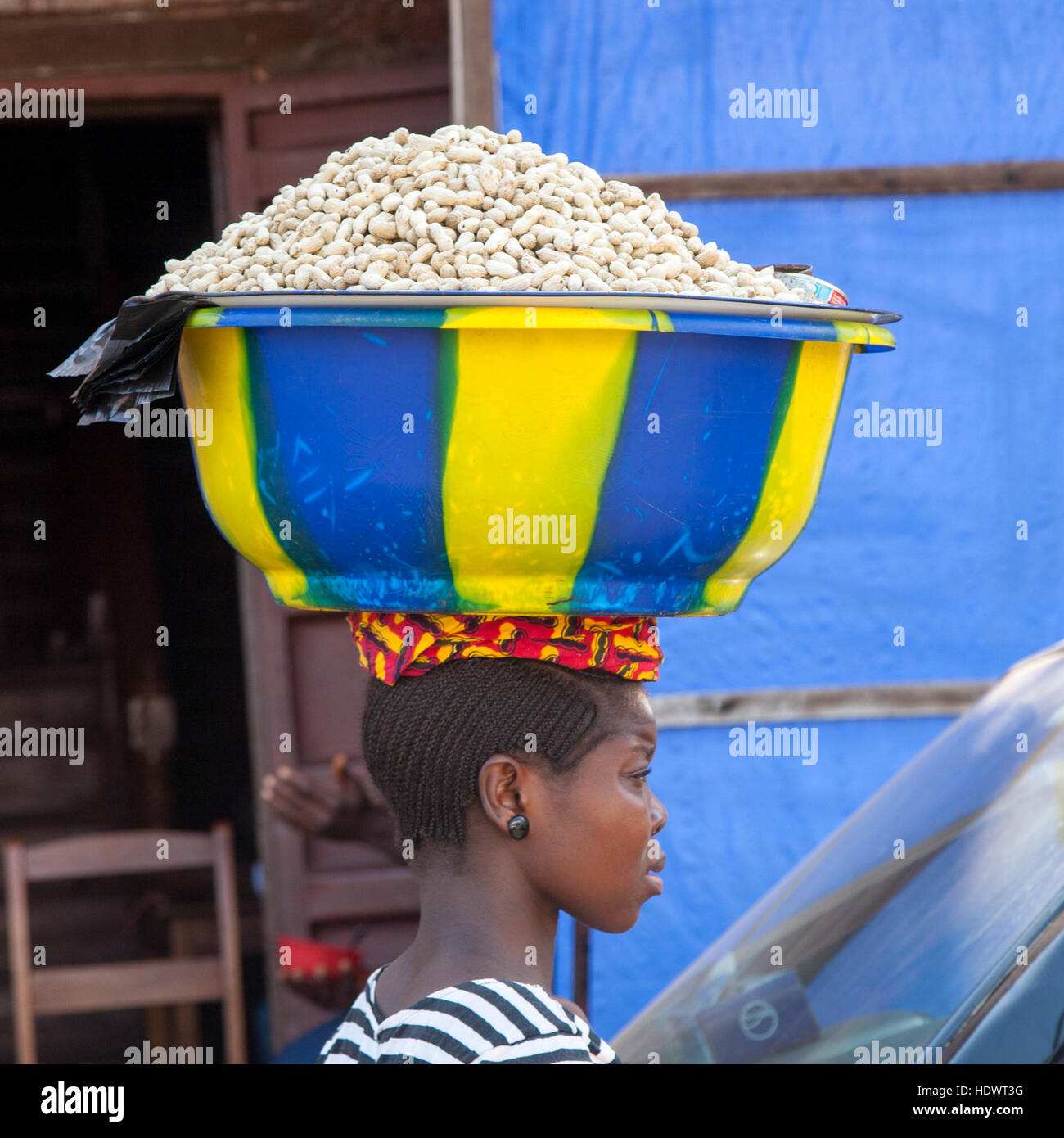 Afrikanische Verkäuferin trägt eine Schale Erdnüsse auf ihrem Kopf Stockfoto