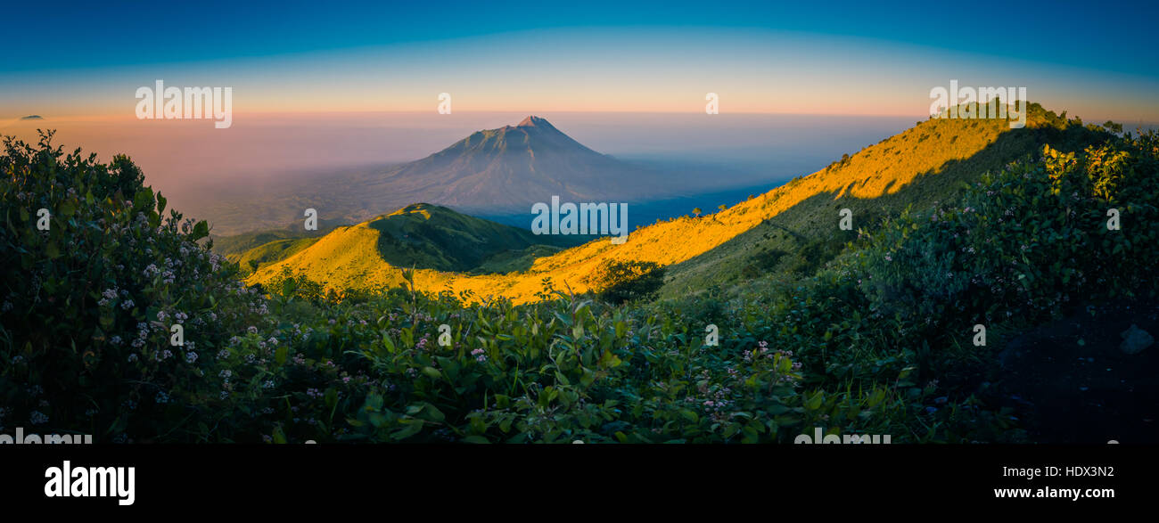 Panorama-Foto von Bergen und Mount Merbabu bedeckt mit Sonne und Nebel bei Sonnenaufgang in der Nähe von Yogya in Zentral-Java Provinz in Indonesien. In diesem Stockfoto