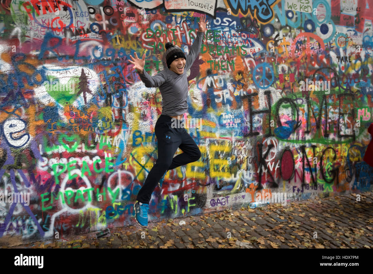 Ein junger Besucher springt vor dem John-Lennon-Mauer in Malá Strana, Prag Stockfoto