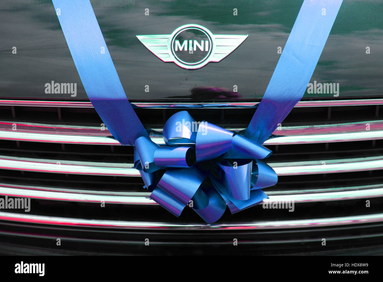 BMW Mini als Hochzeitsauto, gebunden mit einem blauen Band und Bogen über dem Kühlergrill. Stockfoto