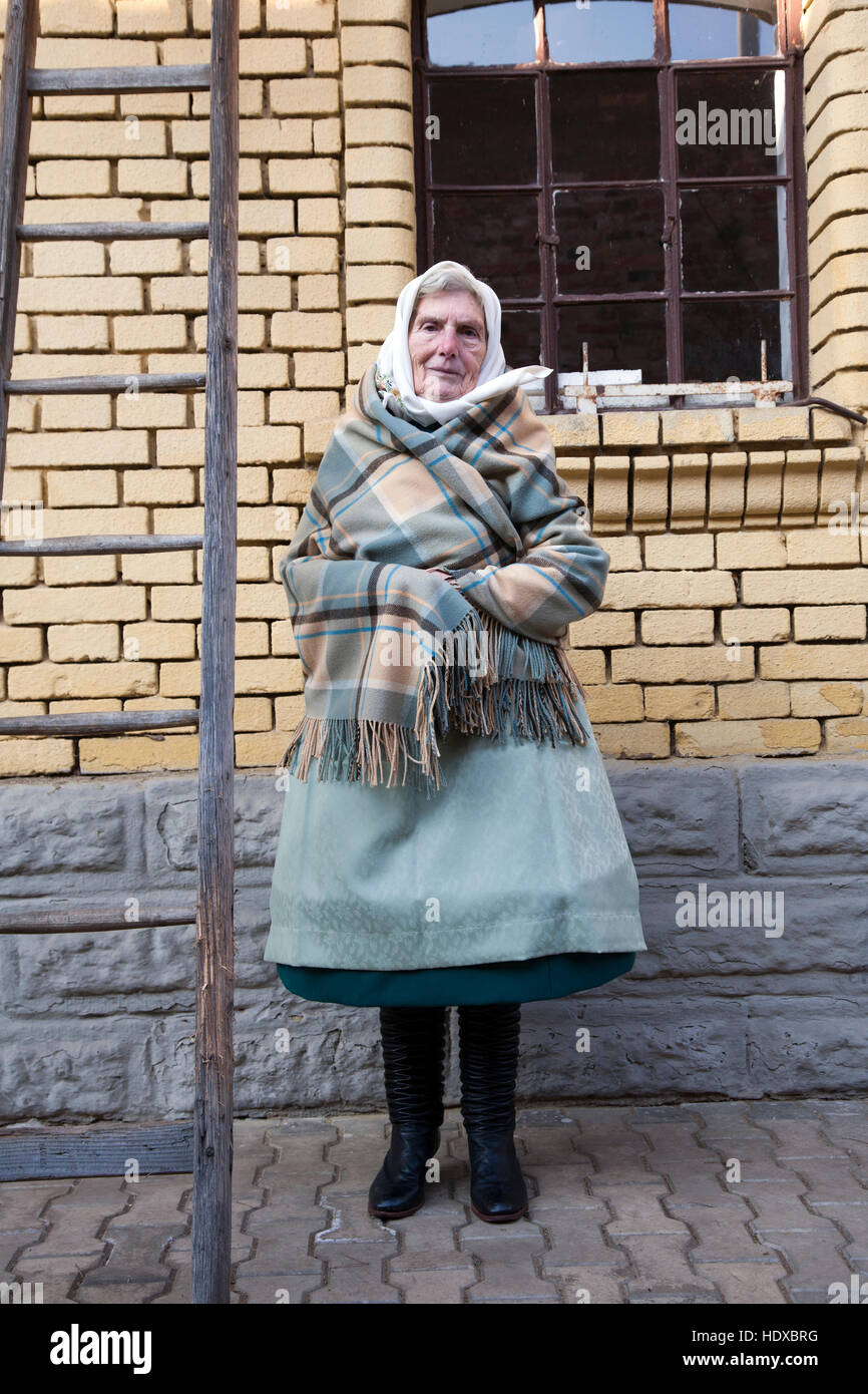 Frau trägt Tracht der Region Posen vor ihrem traditionellen Haus in Mähren Stockfoto