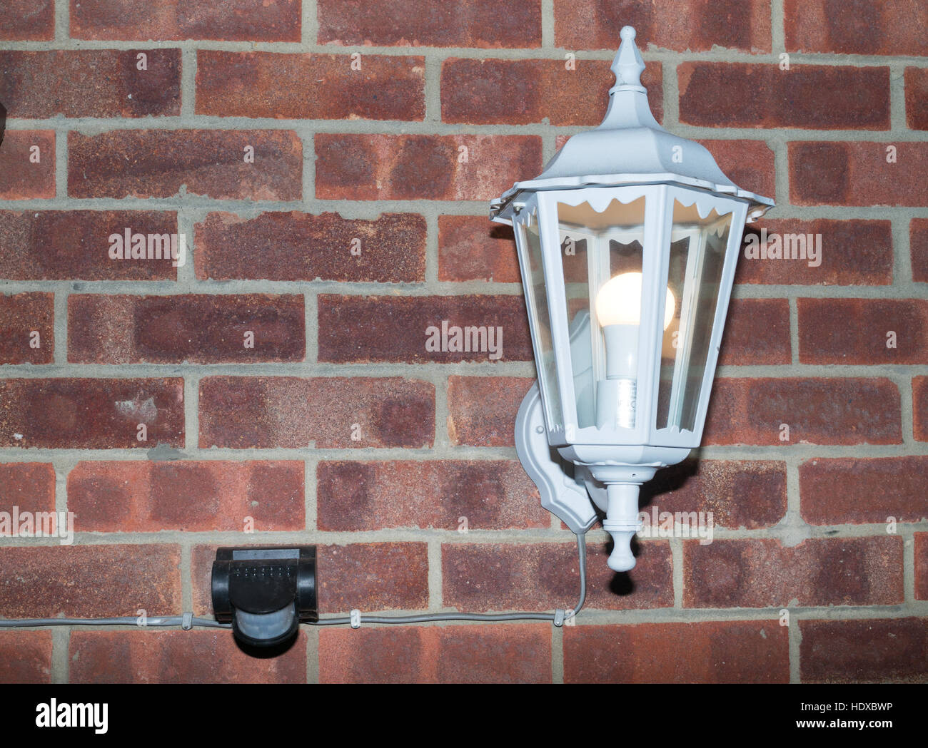 Outdoor-Laterne mit LED-Lampe von PIR-Bewegungsmelder gesteuert auf eine äußere Mauer montiert. Stockfoto