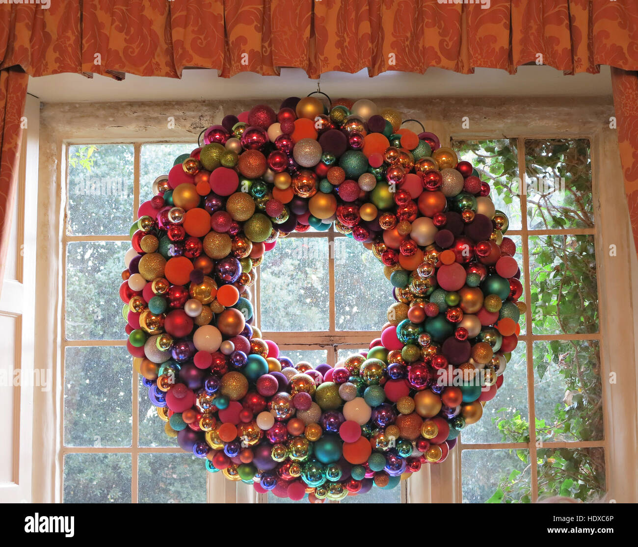 Großer Adventskranz gemacht von bunten Kugeln hängen im Fenster Stockfotografie
