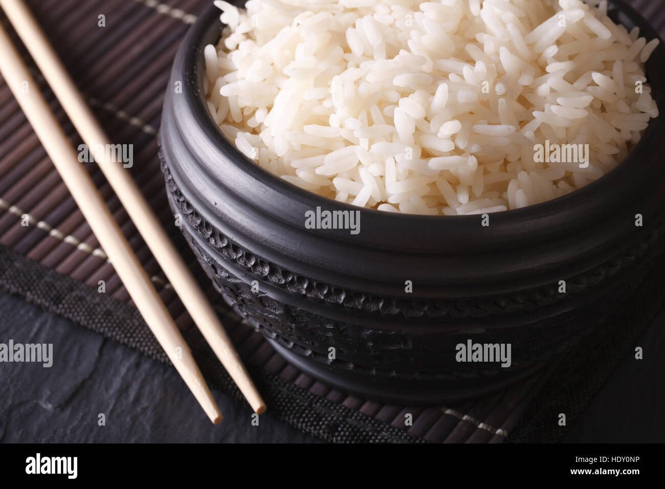 Asiatische Küche: gekochten Reis in ein Makro schwarze Schale und Stäbchen. horizontale Stockfoto