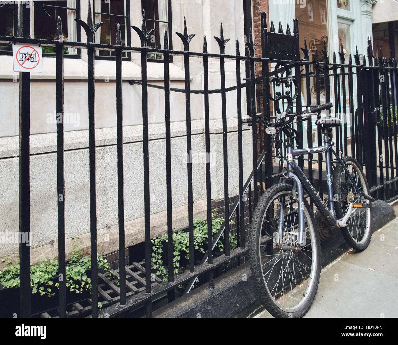 Fahrrad angekettet an Geländern, wo ein "Fahrrad verboten" Schild angezeigt wird. Stockfoto