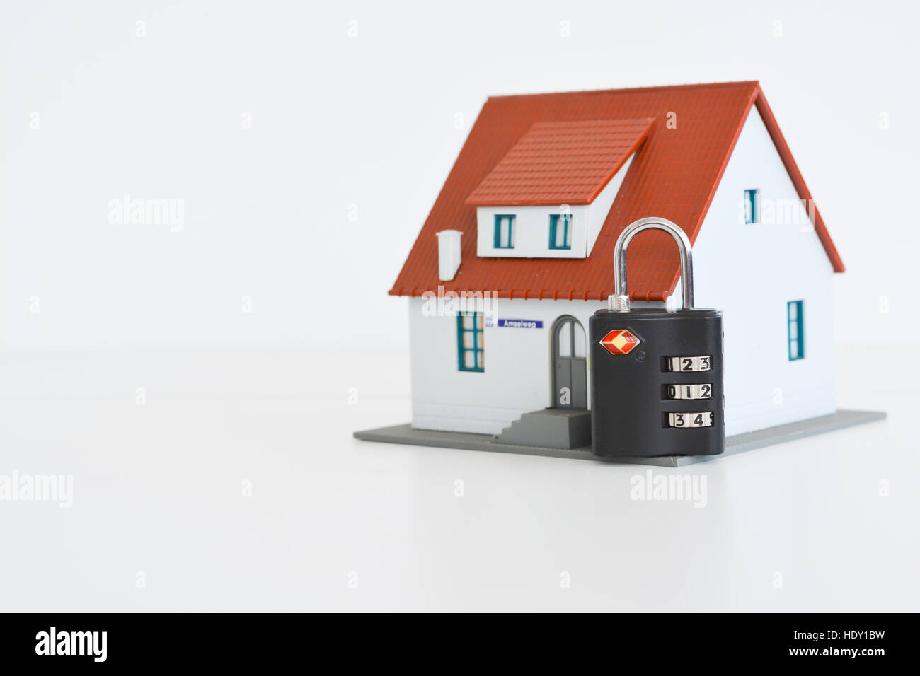 Das Konzept des inländischen Wertpapieres oder Versicherungen mit Chiffre Schloss statt, abgesehen von einem Miniaturhaus Stockfoto