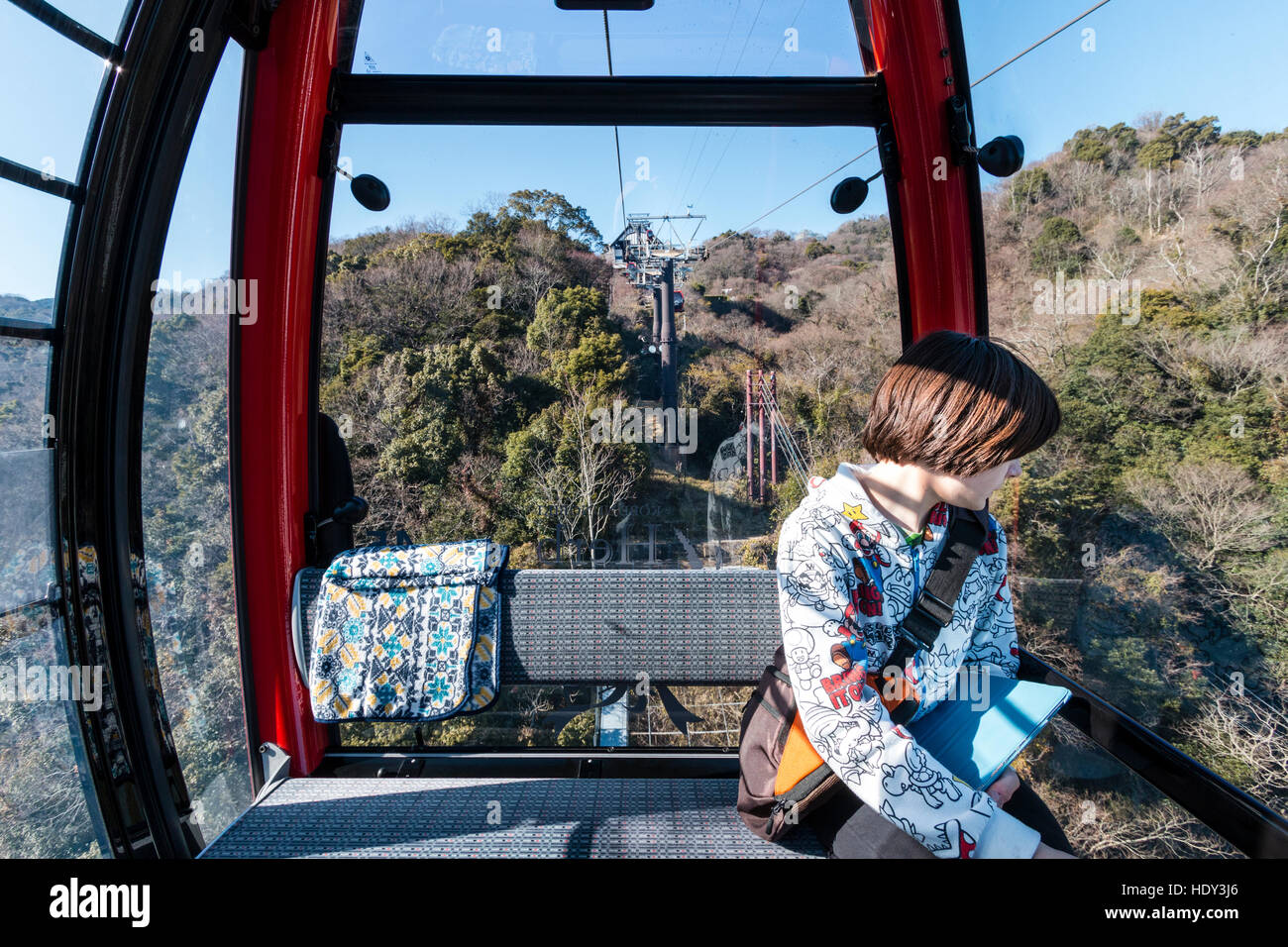 Japan, Kobe. Kaukasier Kind, Junge männliche Teenager, in der Seilbahn auf Shin-Seilbahn, ipad Holding beim Blick aus dem Fenster an Rokko Berglandschaft. Stockfoto