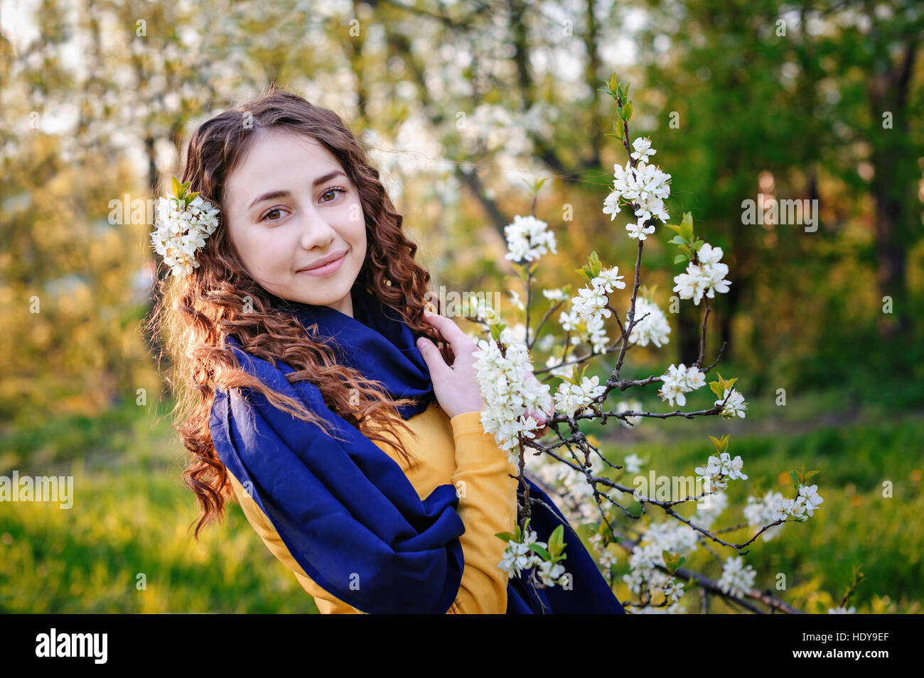 glückliche junge Frau in der Nähe ein blühender Baum im Park Stockfoto