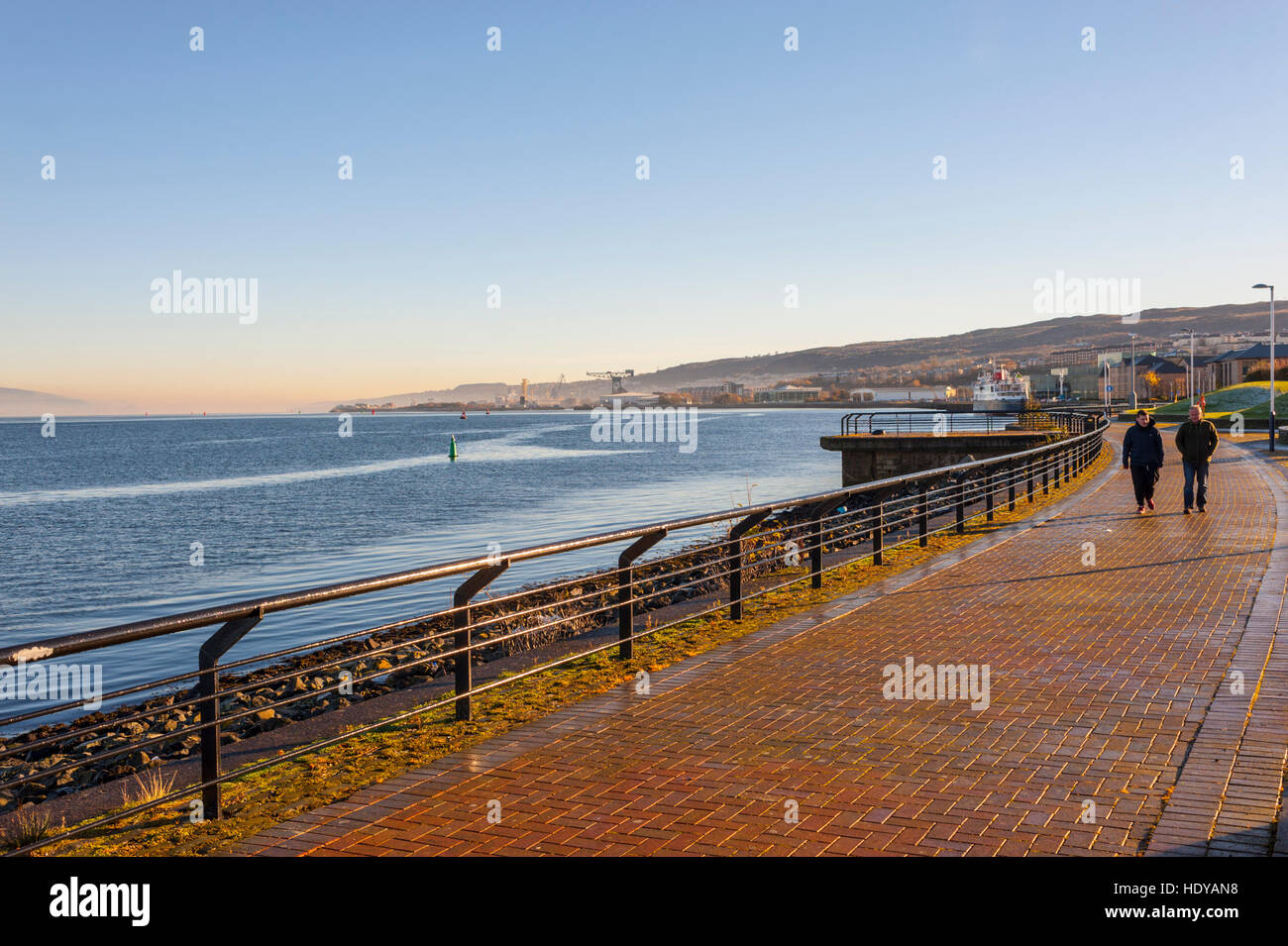 Zwei Menschen zu Fuß Alomg die neue Esplanade in Greenock an einem kalten Wintermorgen mit Nebel am Fluss. Stockfoto