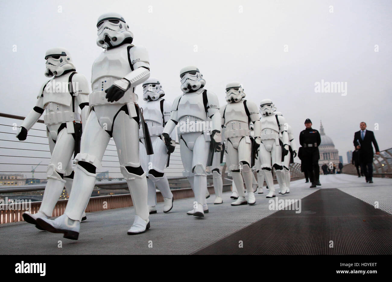 Eine Gruppe von Star Wars-Fans, die als Stormtrooper verkleidet sind, gehen über die Millennium Bridge in London, um den Start von Rogue One: A Star Wars Story zu feiern, der heute landesweit veröffentlicht wird. Stockfoto