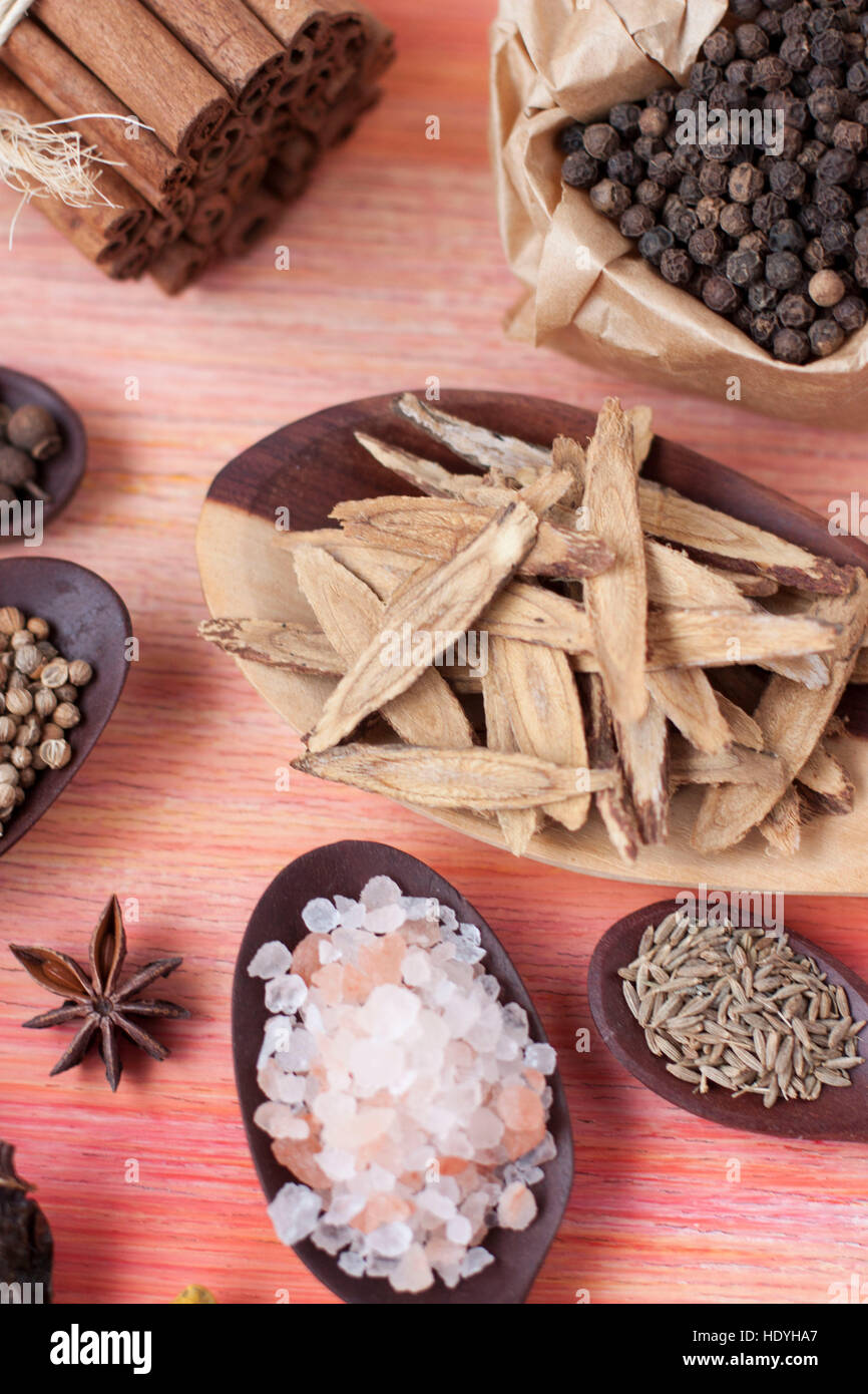 Gewürze in einem rosa Hintergrund - Lakritz, schwarzer Pfeffer, rosa Salz, Sternanis, Zimt und kummel Stockfoto