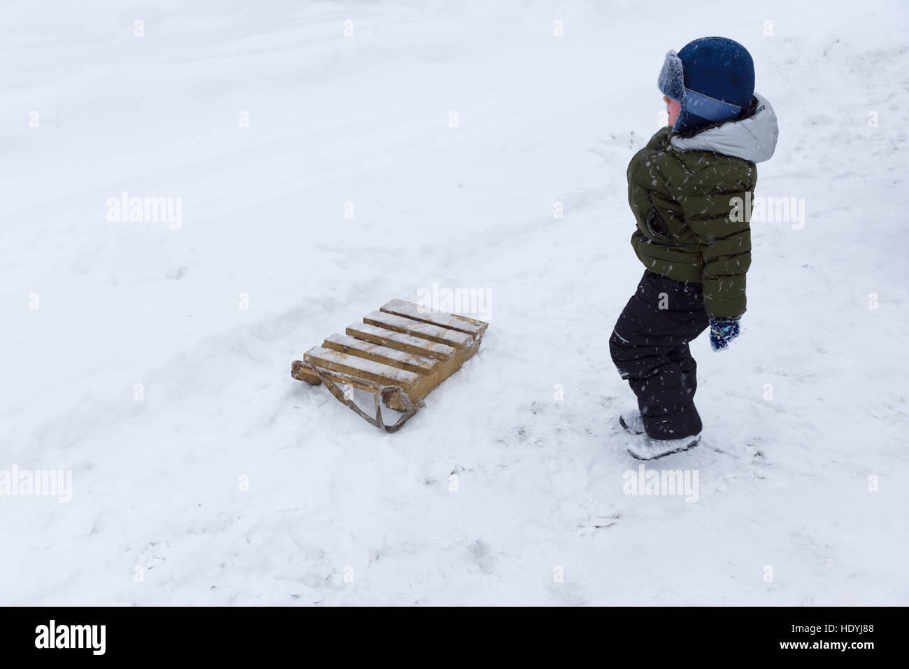 Junge mit Schlitten bestehen aus Planken auf dem Schnee im winter Stockfoto