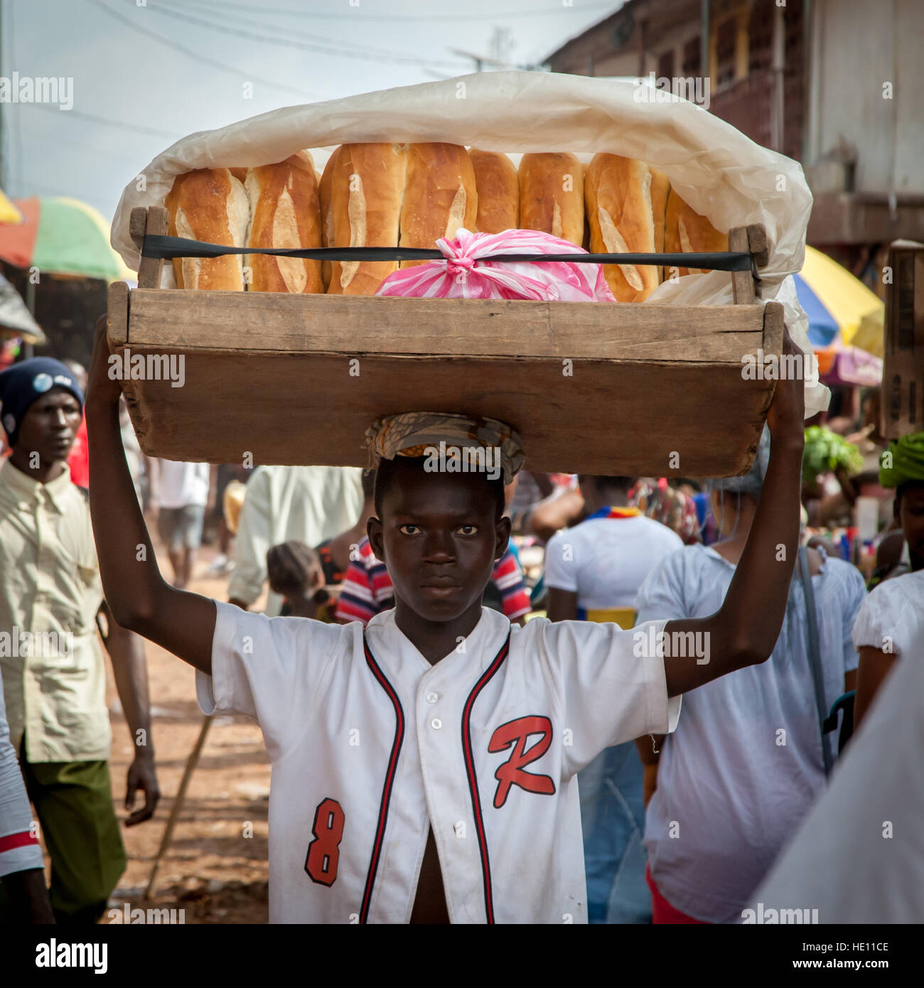 Afrikanischer Jugendlicher mit einem Tablett Brot Brote Stockfoto