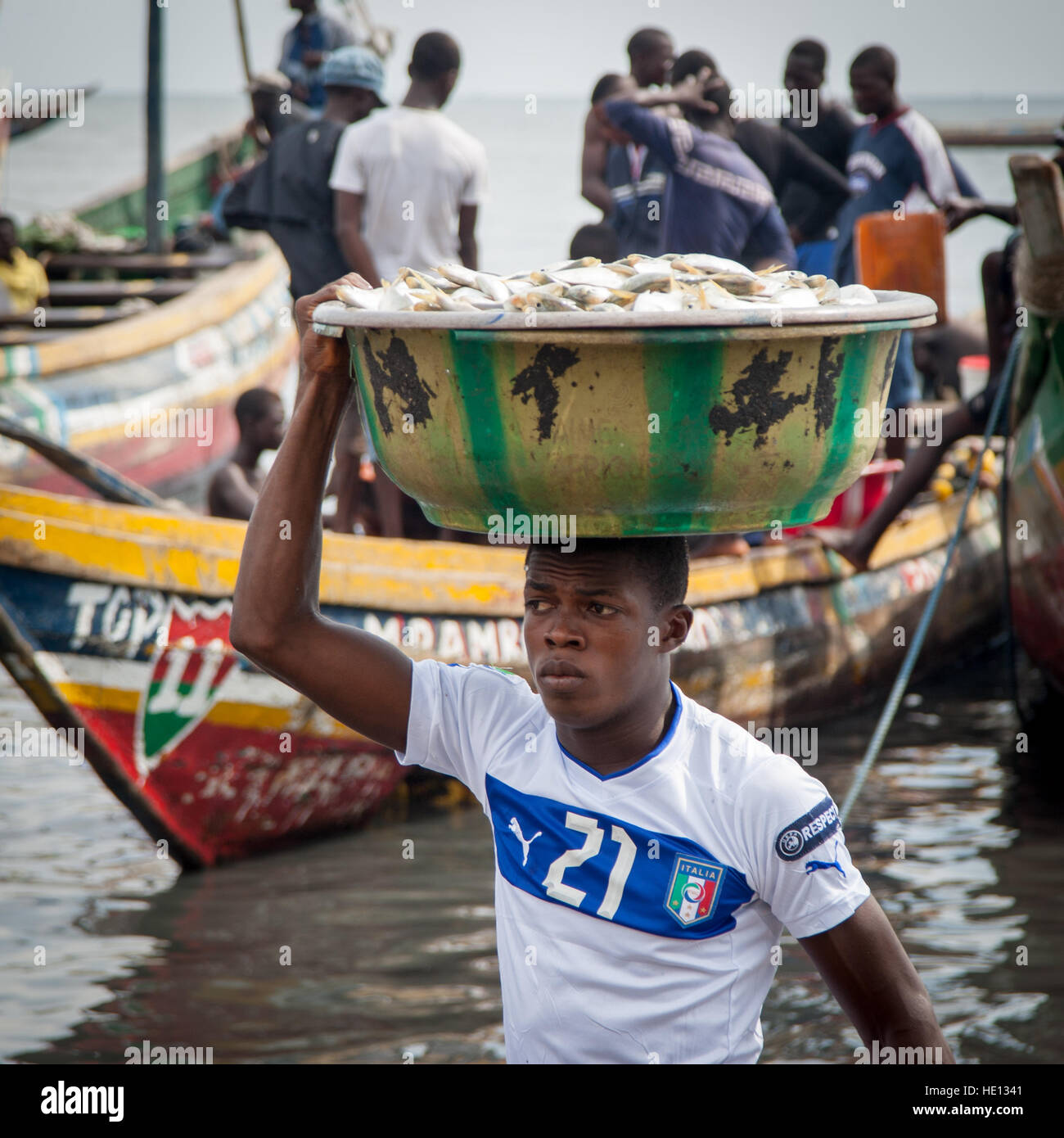 Junger afrikaner in Tombo, Sierra Leone, trägt eine große Schüssel Fisch von Schiff zu Ufer. 30 Kilo Fisch werden in Sierra Leone mit Haltung transportiert Stockfoto