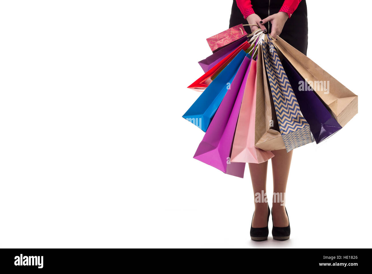 Unteren Nahaufnahme stehende Frau mit kurzen Rock und Schuhe mit hohen Bergen, die mit bunten einkaufen Papiertüten und Pakete, isoliert am Pfingstmontag Stockfoto