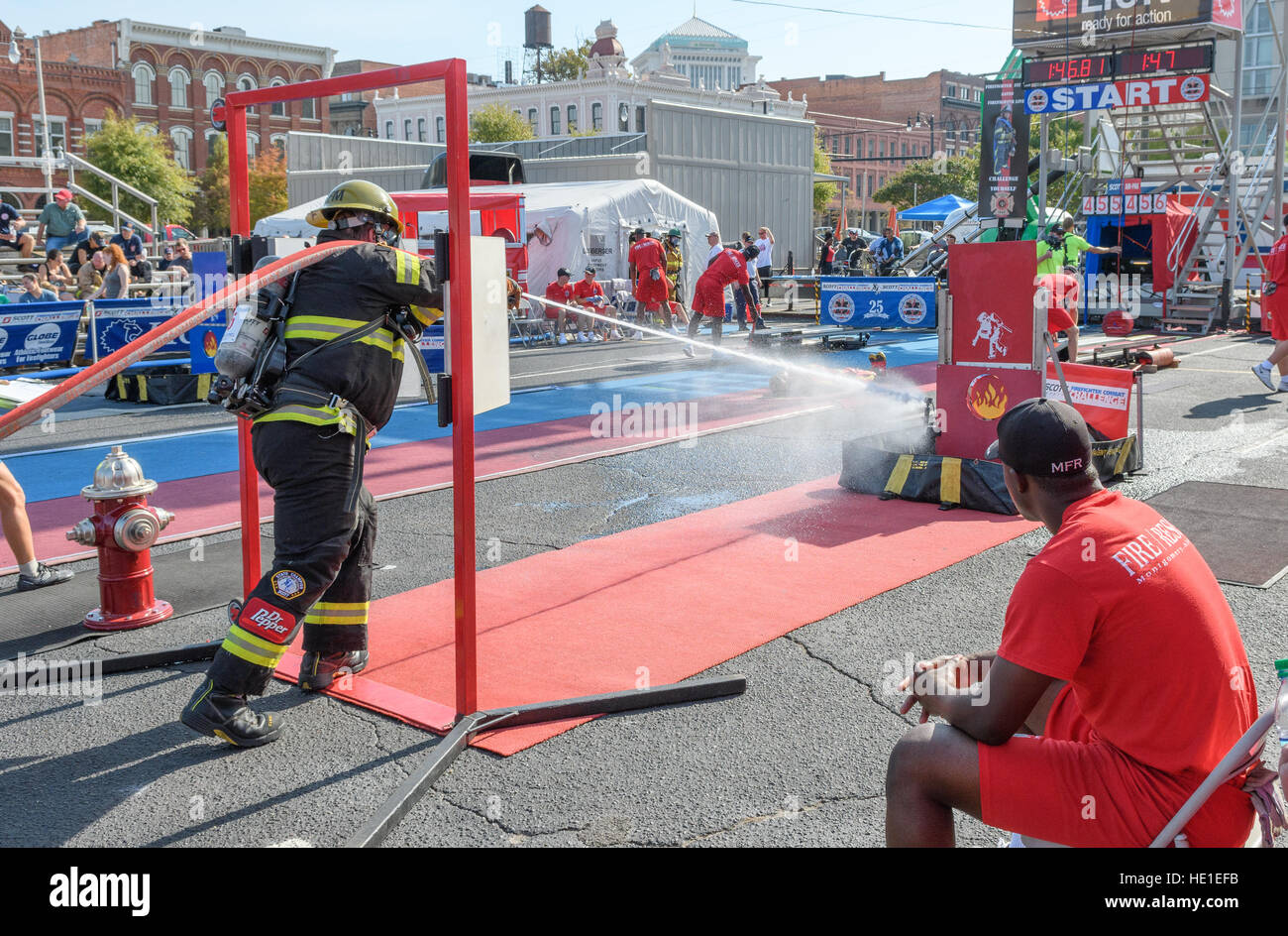 Ein Feuerwehrmann ein Ereignis mit Zeitangabe mit einem Feuerwehrschlauch. Stockfoto