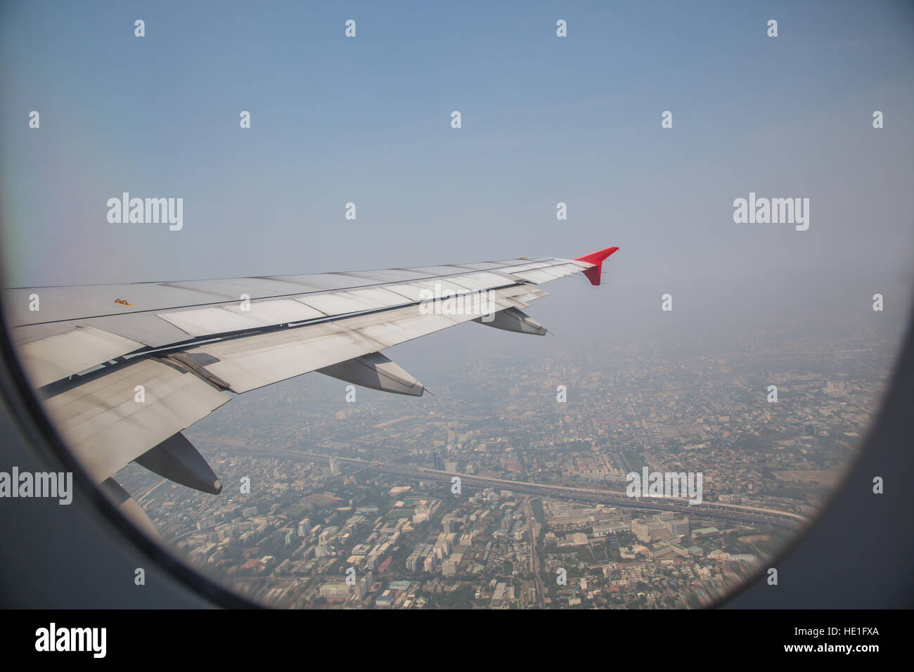 Blick durch ein Fenster von einem Flugzeug Flugzeuge fliegen über Land und blauer Himmel. Stockfoto