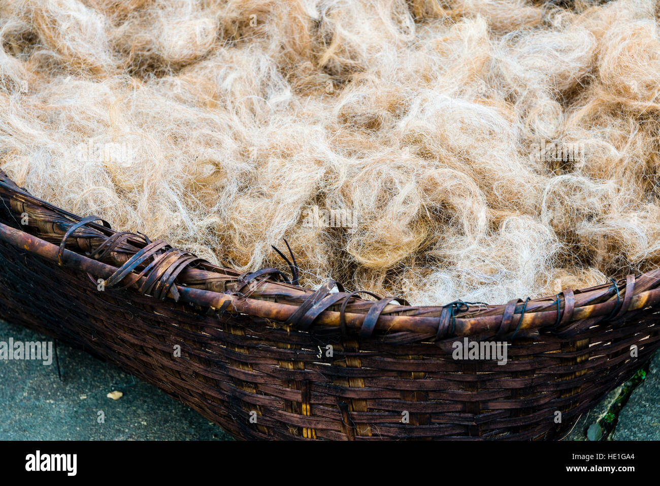 Rohstoff Schafwolle in einem geflochtenen Korb, bereit für die Spinnerei Stockfoto
