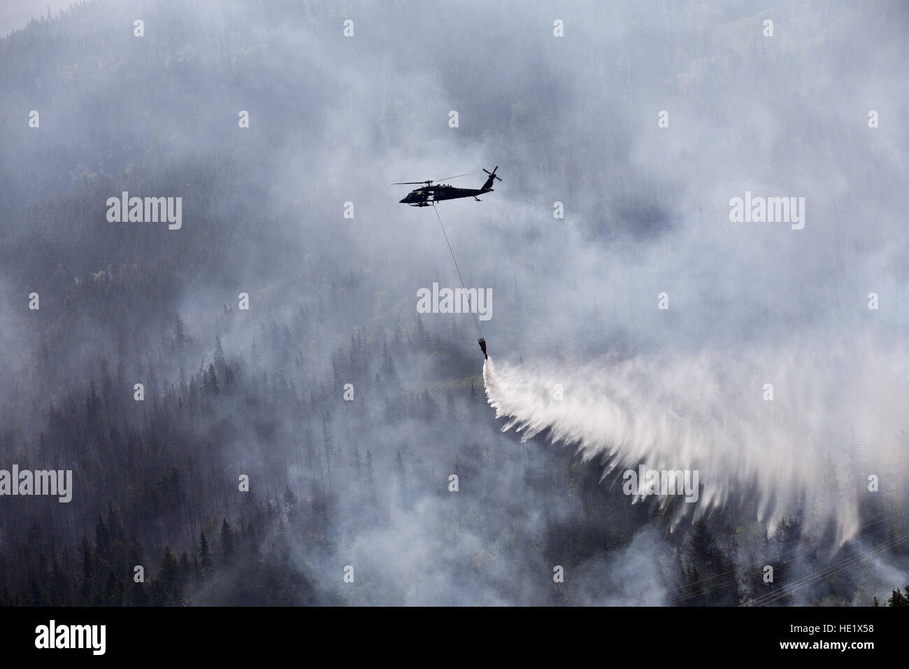 Ein Alaska Army National Guard UH-60 Black Hawk vom 1. Bataillon, 207. Aviation Regiment fällt ungefähr 700 Gallonen Wasser aus einem ÒBambi BucketÓ auf die Stetson-Creek-Feuer in der Nähe von Cooper Landing, Alaska, 17. Juni 2015. Zwei Black Hawks flog insgesamt 200 Eimer Missionen, dumping mehr als 144.000 Gallonen Wasser auf dem 300 Hektar großen Stetson Creek Feuer auf der Kenai-Halbinsel. US Army National Guard Foto/Sgt. Balinda OÕNeal Alaska Army National Guard Stockfoto