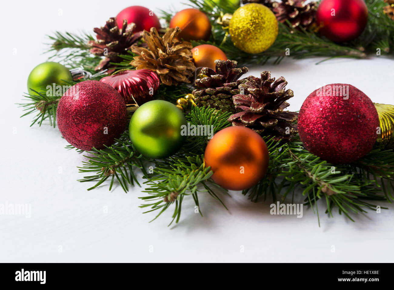 Weihnachtsbaum Äste mit rot, grün, orange und gelben Ornamenten. Weihnachts-Dekoration mit goldenen verzierten Tannenzapfen. Adventskranz mit mu Stockfoto