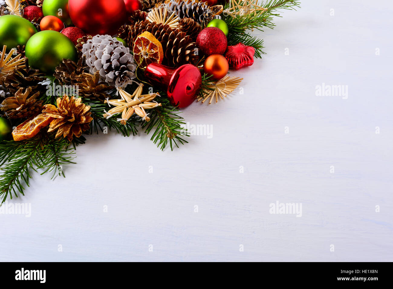 Rote und grüne Weihnachtsschmuck, Tannenzweigen und Tannenzapfen. Weihnachts-Dekoration mit Jingle Bell und getrocknete Orangenscheiben. Weihnachtsgruß zurück Stockfoto