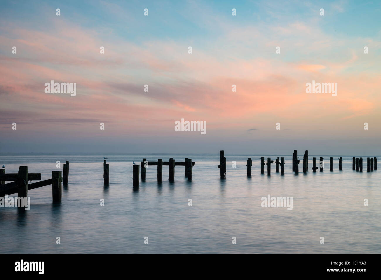 Langzeitbelichtung Landschaftsbild der farbenfrohen Sonnenaufgang über dem Meer und verlassenen Pier im Abstand Stockfoto